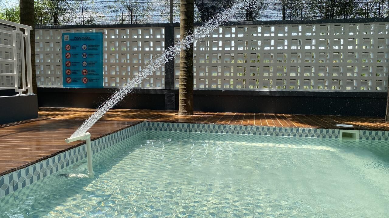 A clear pool with a wooden deck and a blue sign with pool rules.