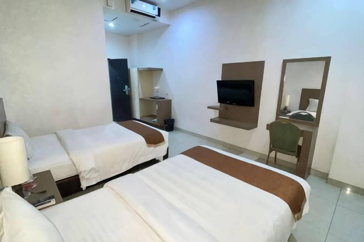 A hotel room with two beds, a TV, a desk, and a chair.