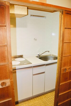 Een kleine keuken met een spoelbak, fornuis en kastjes.