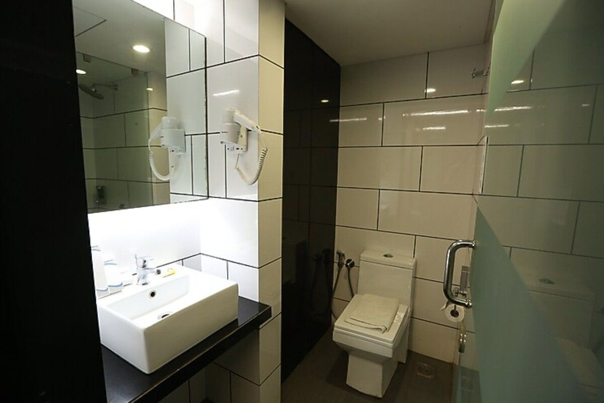 A modern bathroom with a white sink, mirror, and toilet.