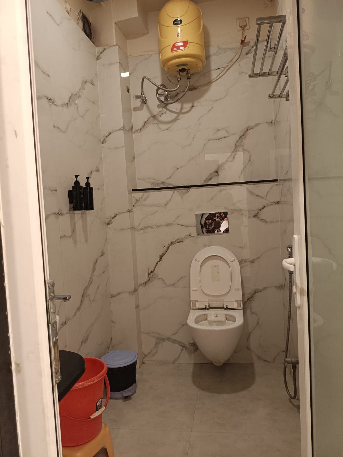 Et badeværelse med toilet, bruser og væg i marmor.