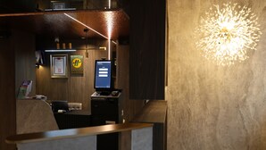 En receptionsdisk med en dator, inramade certifikat och en väggmonterad lampa.