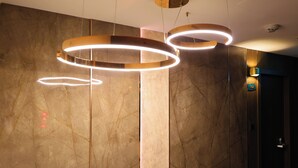 En modern inredning med en vägg av marmor, en rund lampa och en dörr med ett nummerskylt.