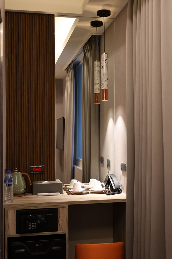 Habitación de hotel con pared de paneles de madera, escritorio con cafetera, teléfono y microondas.