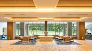 A spacious lobby with a central bar area, large windows offering a view of the outdoors, and a modern ceiling design. - Urabandai Grandeco Tokyu Hotel (Kitashiobara)