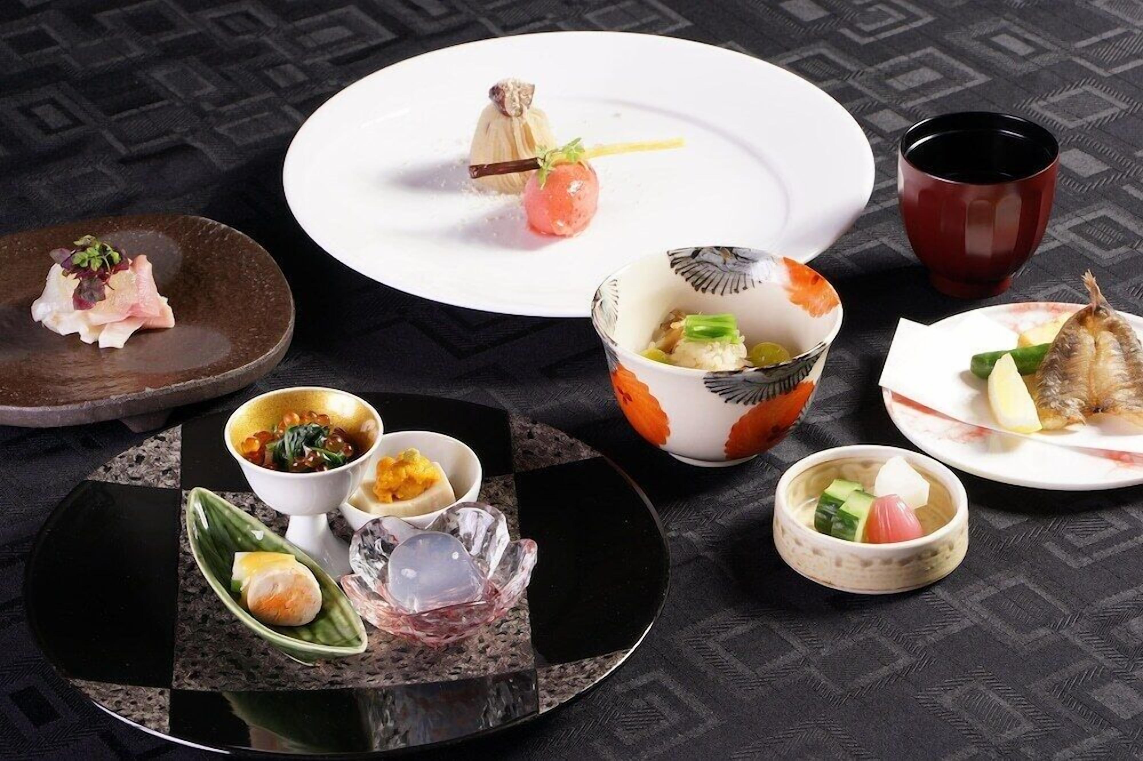 A variety of dishes on a table, including sushi, sashimi, and small bowls of food.