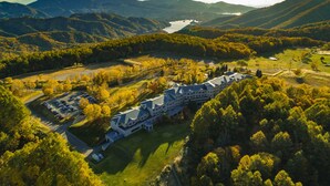 A large, multi-story hotel with a symmetrical roofline, surrounded by lush greenery and a mountainous backdrop. - Urabandai Grandeco Tokyu Hotel (Kitashiobara)