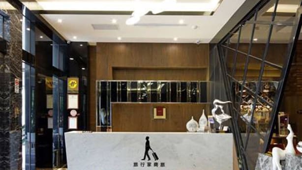 A hotel reception area with a marble counter, a large chandelier, and a checkered floor.