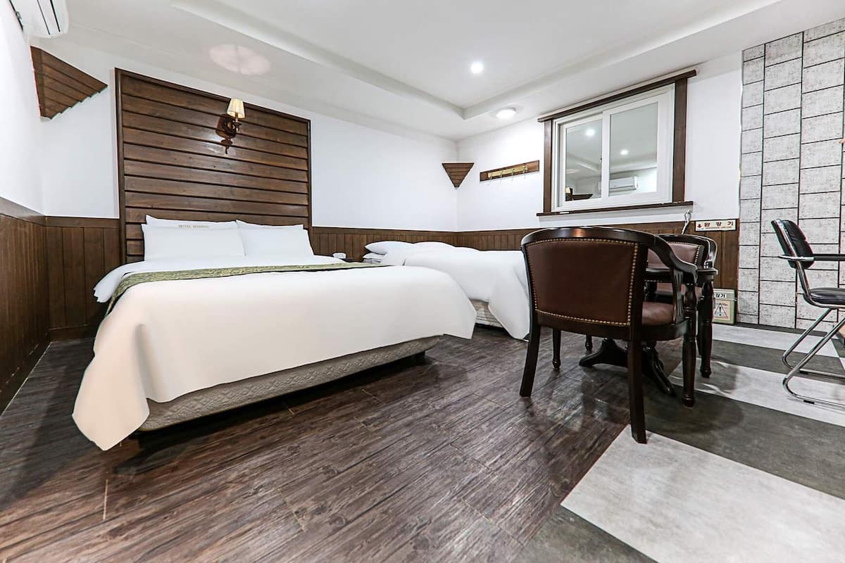 A hotel room with a large bed, a desk, and a chair.