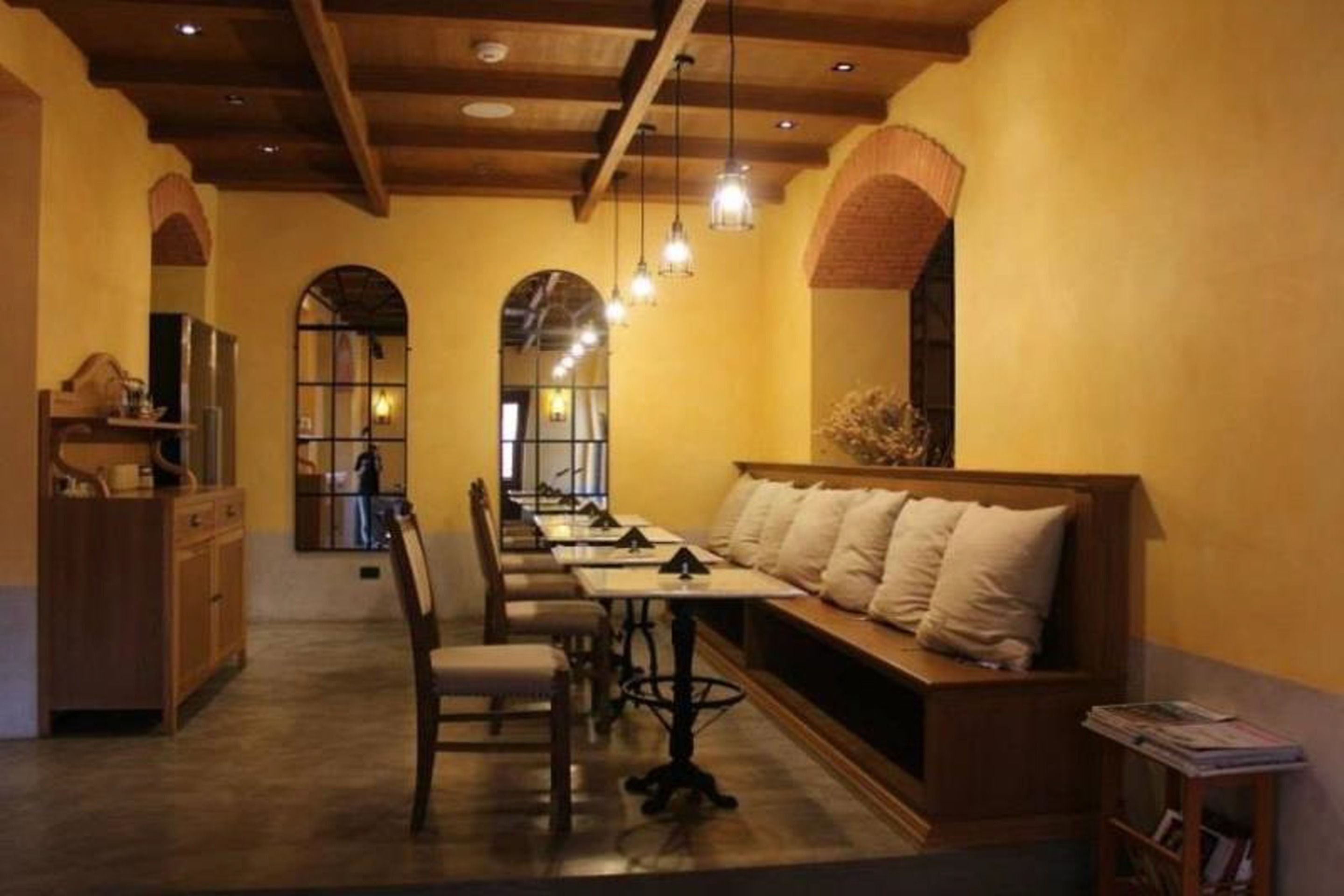 Un restaurante acogedor con mobiliario de madera, una barra larga y un banco con cojines.