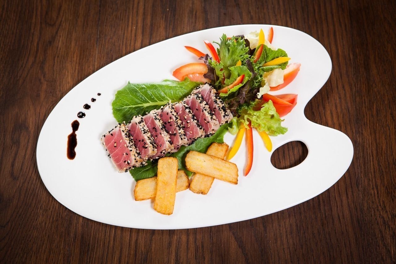 Prato com salada, batatas fritas e fatias de atum.