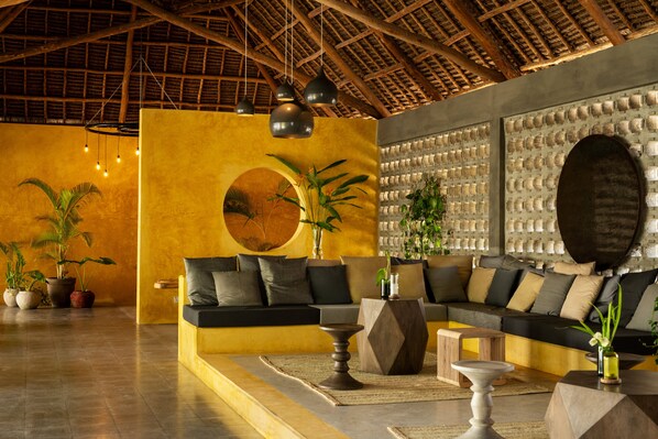 A modern living room with a sofa set, a coffee table, and a decorative wall with a circular pattern. - Casa Beach Hotel - Casa del Mar (Jambiani)