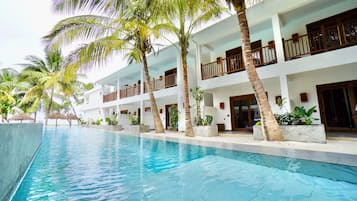A resort with a swimming pool, palm trees, and a multi-story building with balconies.