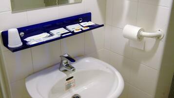 A bathroom with a white sink, a blue shelf with toiletries, and a toilet paper holder.