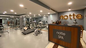 Un gimnàs amb diverses màquines d'exercici i una recepció amb el nom 'notte SPA'.