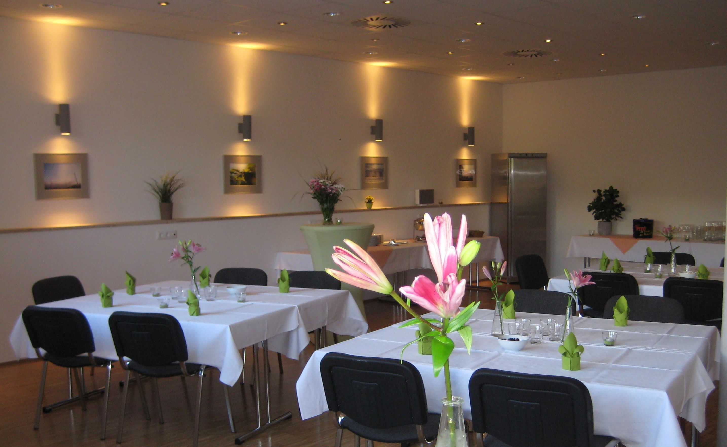 A dining area with tables set for a meal, chairs, and decorative vases with flowers.