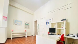 A room with a desk, computer, and chair, a whiteboard with text, and a map on the wall. - Castelnuovo Rooms  (Palermo)