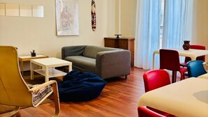 A modern living room with a sofa, a coffee table, a dining table with chairs, and a wooden floor. - Castelnuovo Rooms  (Palermo)