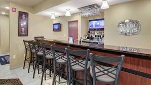A bar area with a counter, bar stools, a television screen, and a sign that says "FULL OF CHEER AND GOOD SPIRITS". - Cobblestone Hotel & Suites - Waynesboro (Waynesboro)