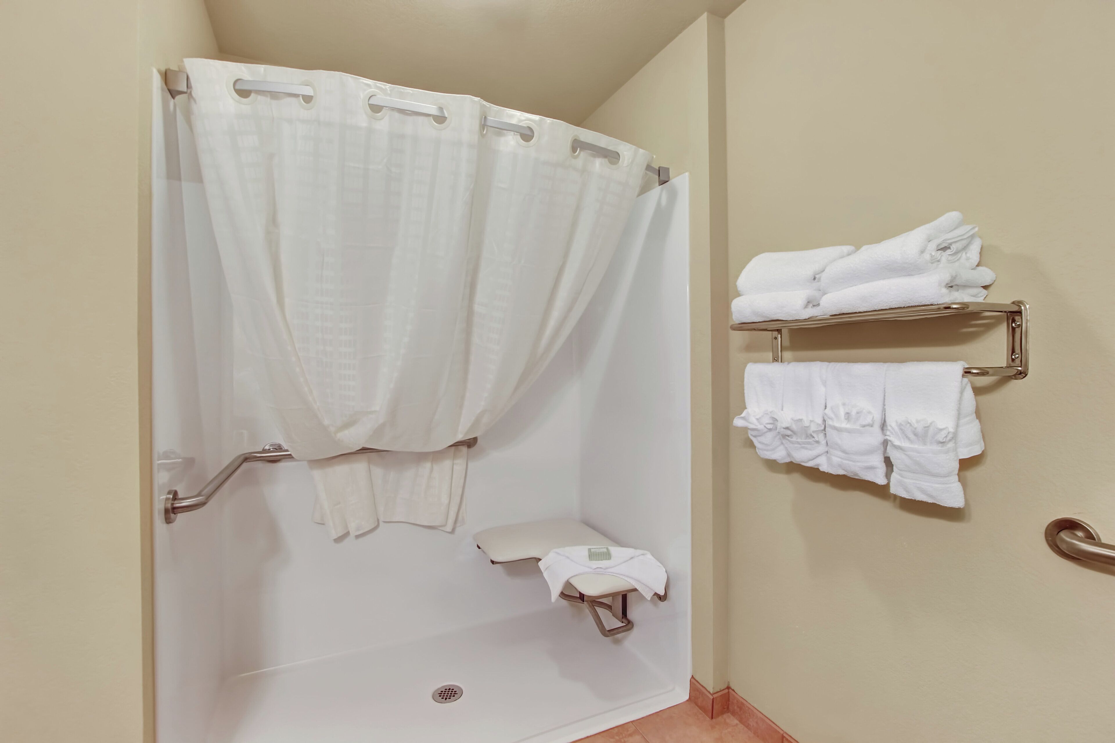 A bathroom with a shower curtain, a toilet, and a towel rack with folded towels.