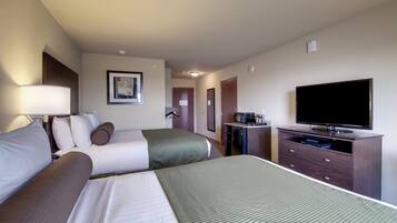 A hotel room with two beds, a television, a desk with a computer, and a framed picture on the wall.
