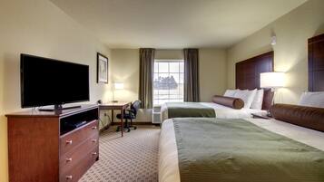 A hotel room with a flat-screen TV, a desk, two beds, and a window with curtains.
