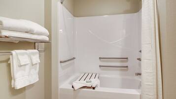 A modern bathroom with a bathtub, a towel rack with folded towels, and a shower curtain.