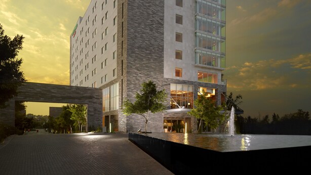A modern hotel with a multi-story structure, large windows, and a well-lit entrance. - Courtyard by Marriott Queretaro (Querétaro)
