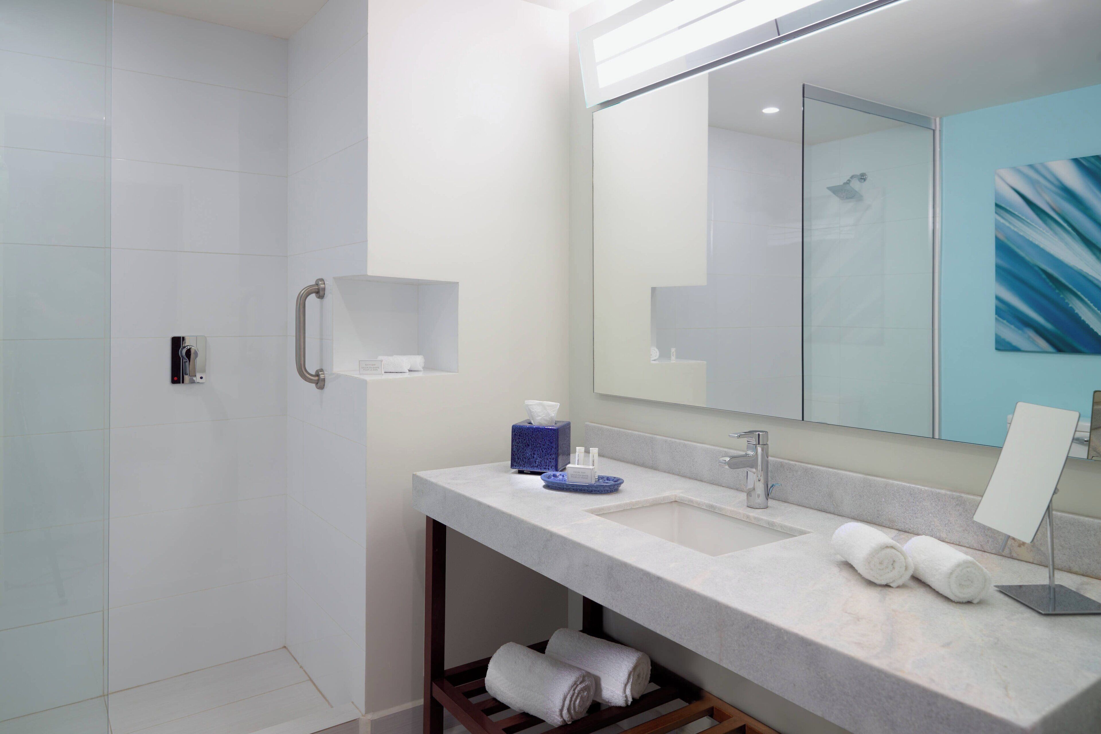 A modern bathroom with a large mirror, a sink, and a shower.