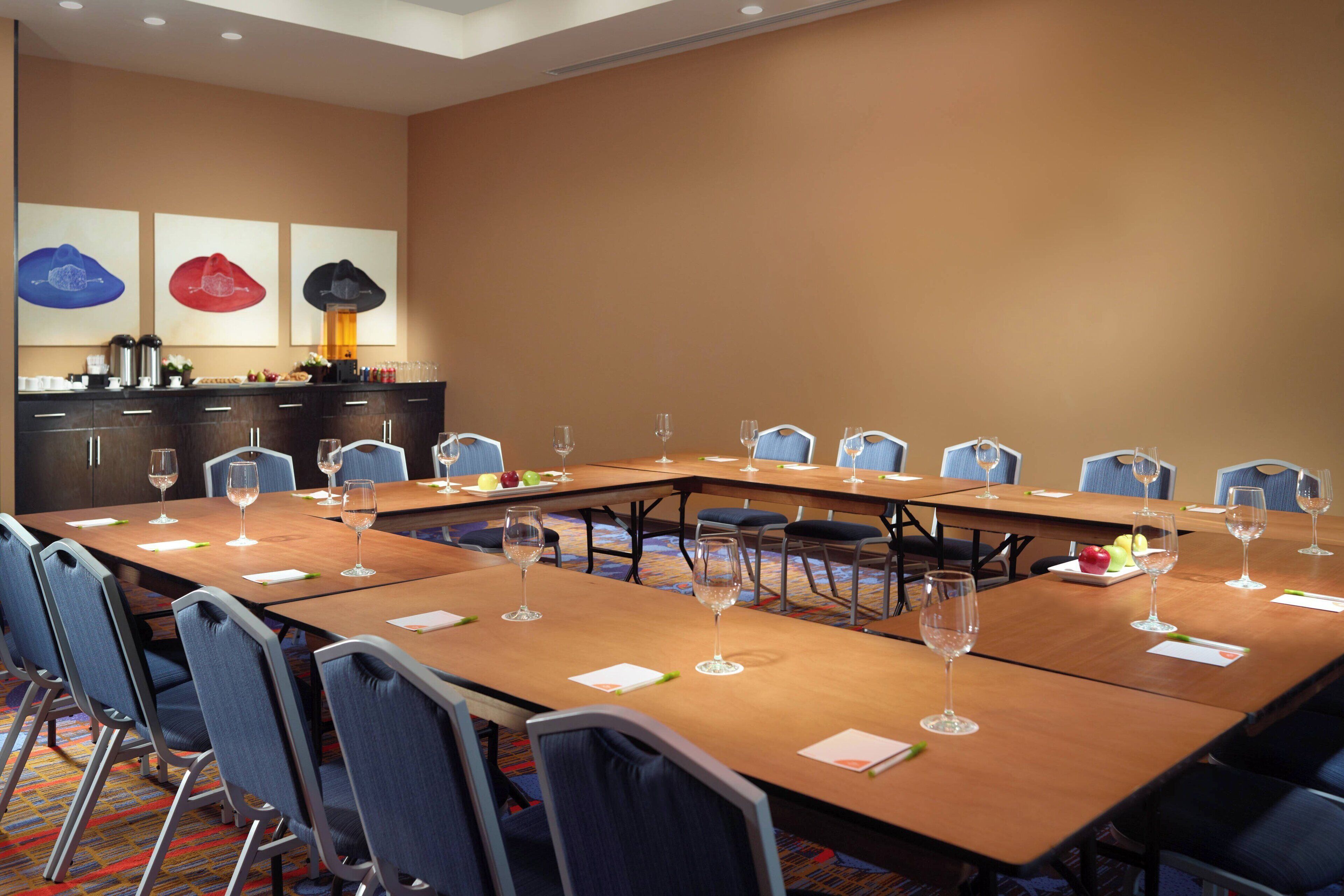 Un salón de conferencias con una mesa larga, sillas y una estación de café.