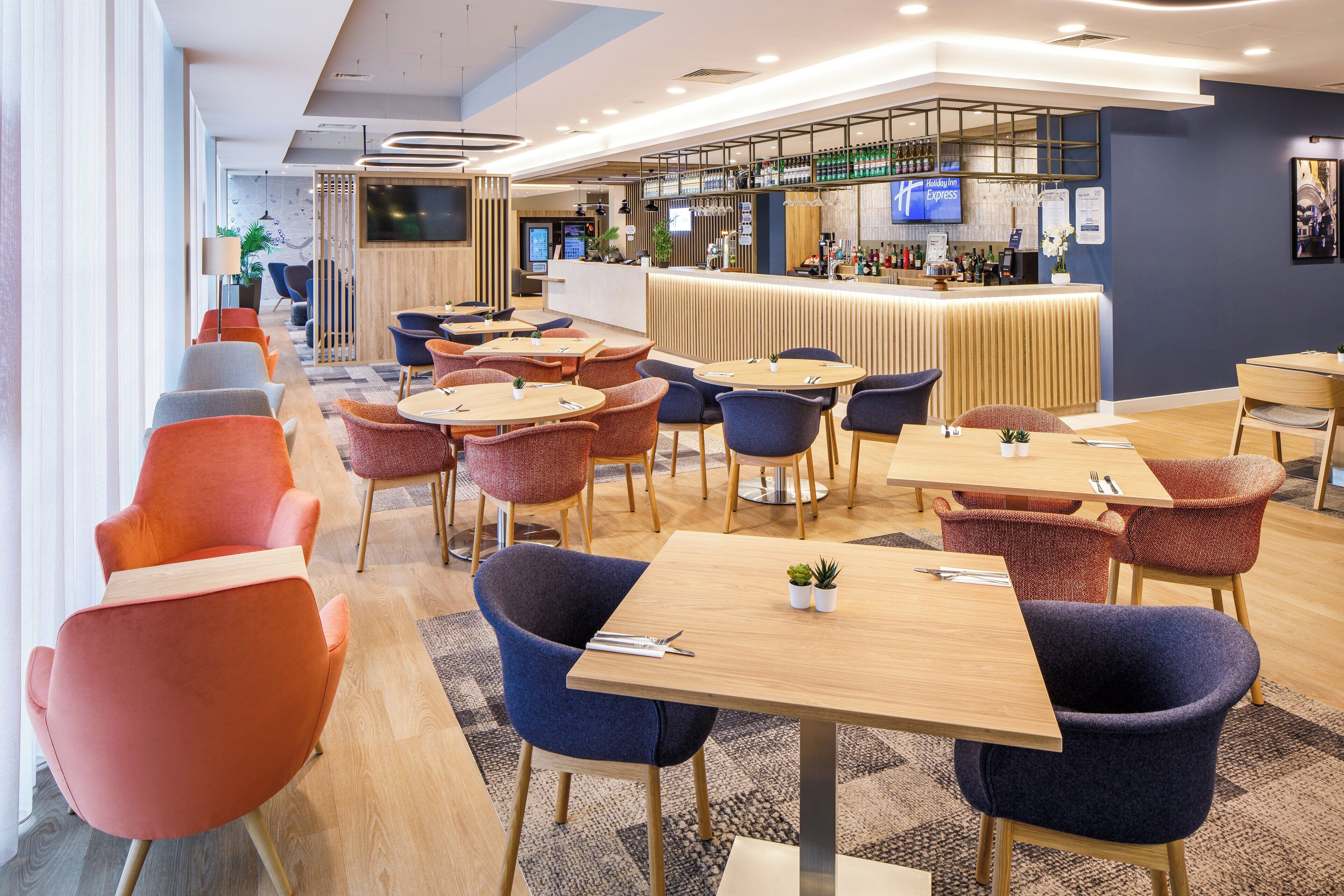 Un moderno vestíbulo de hotel con una zona de bar, asientos y una pantalla de televisión.