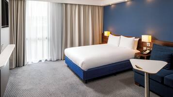 Une chambre d’hôtel avec un lit, des lampes de chevet, un bureau et une chaise.