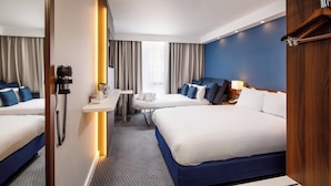 A hotel room with two beds, a desk, a chair, a telephone, and a window with curtains.