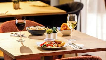 Una mesa de comedor con un plato de comida, dos copas de vino y un bol de ensalada.