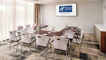 A conference room with a large table, chairs, and a Holiday Inn Express sign on the wall.