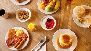 A breakfast spread with various dishes including croissants, eggs, sausages, beans, and fruits. - Holiday Inn Express London - ExCeL by IHG (London)