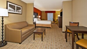 A hotel room with a bed, a sofa, a table, a TV, and a desk with a chair. - Holiday Inn Express & Suites Springfield - Dayton Area by IHG (Springfield)