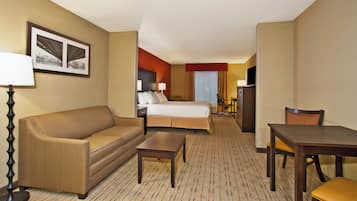 A hotel room with a bed, a sofa, a desk, and a television.