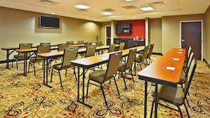 A conference room with long tables and chairs, a flat-screen TV, a kitchenette, and a patterned carpet. - Holiday Inn Express & Suites Springfield - Dayton Area by IHG (Springfield)