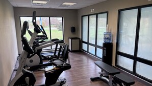 A gym with cardio machines, a bench, and large windows offering a view of the outdoors. - Holiday Inn Express & Suites Springfield - Dayton Area by IHG (Springfield)
