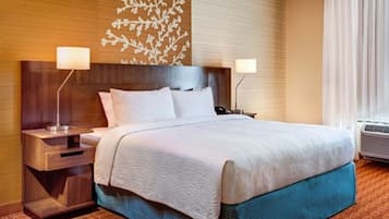 Een hotelkamer met een groot bed, twee bedlampen, een houten hoofdeinde en een decoratief wandpaneel.