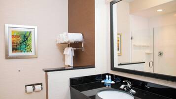 A modern bathroom with a black countertop sink, a large mirror, and a framed artwork on the wall.