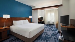 A hotel room with a large bed, a desk, a TV, and a view of the hotel lobby. - Fairfield Inn & Suites Fredericksburg (Fredericksburg)