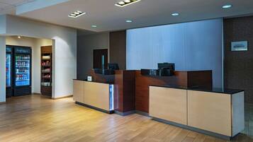 A reception area with a wooden reception desk, a vending machine, and a wall-mounted sign.