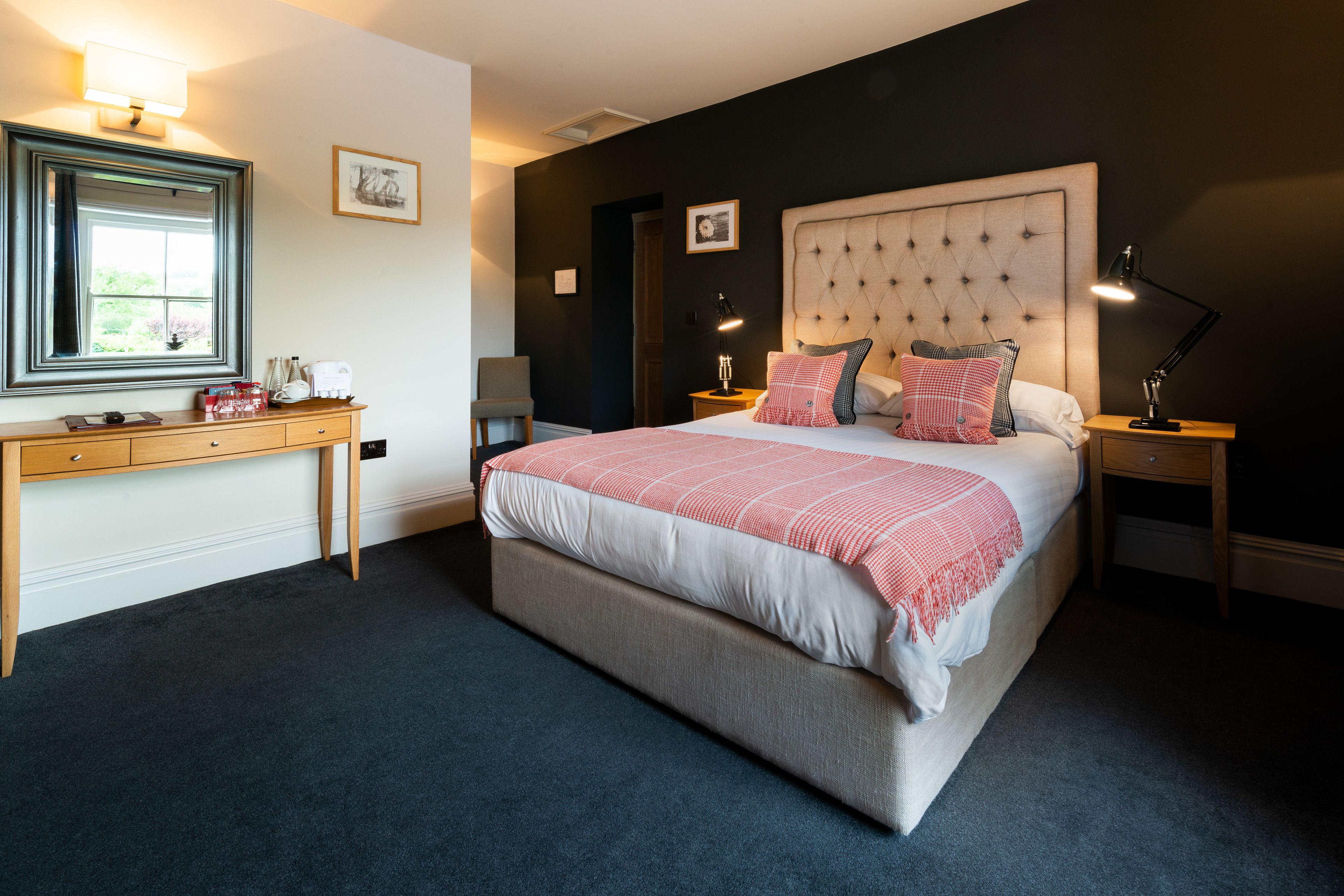 A bedroom with a large bed, bedside tables, a desk, and a window.