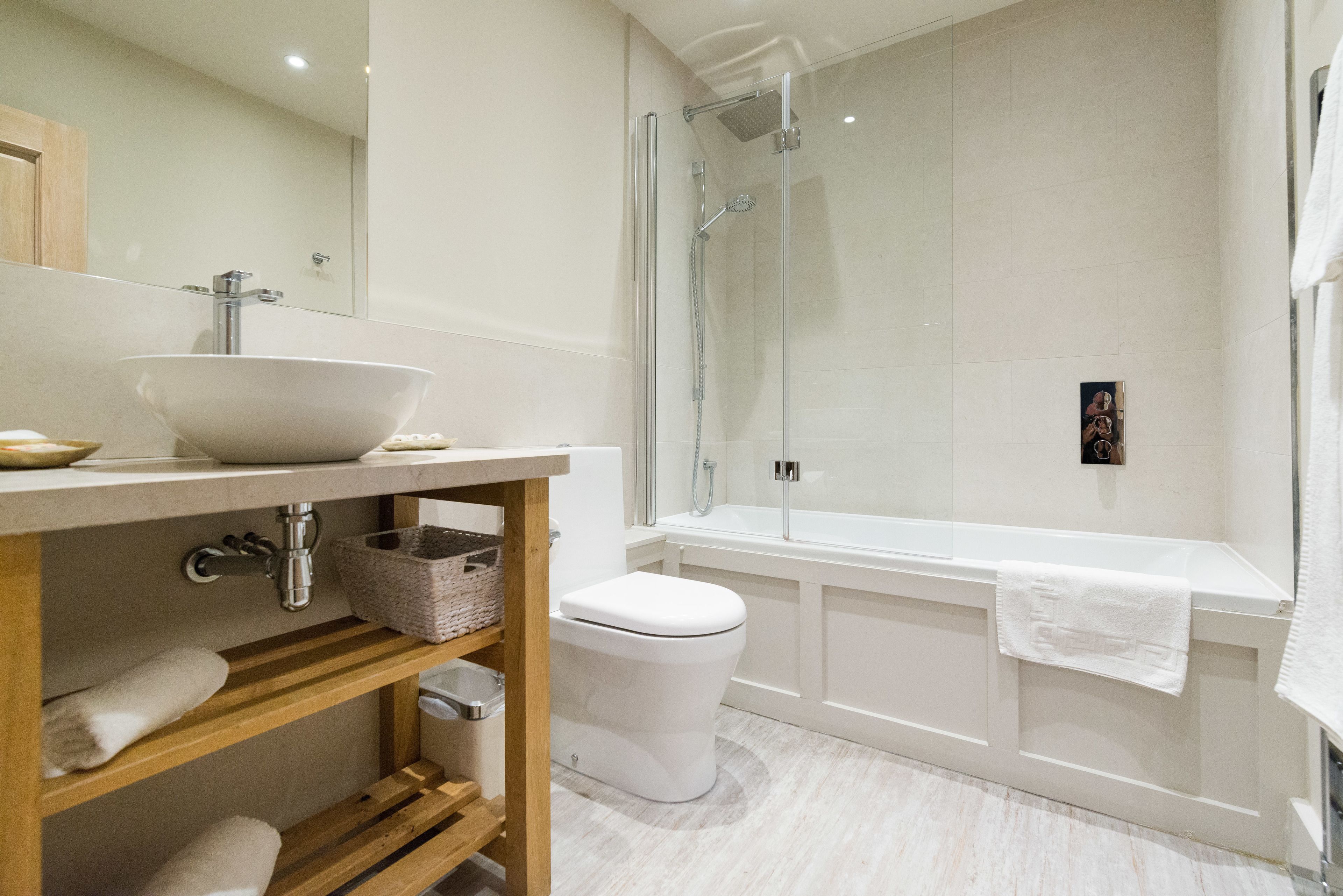 A modern bathroom with a large white sink, a glass-enclosed shower, and a white bathtub.