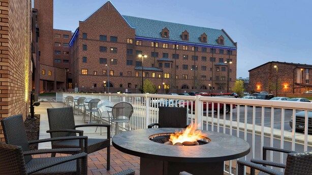A patio with wicker chairs and a round table with a fire pit.