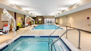 An indoor swimming pool with two lanes, safety railings, and lounge chairs.