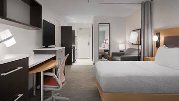A hotel room with a bed, desk, chair, TV, and a mirror.