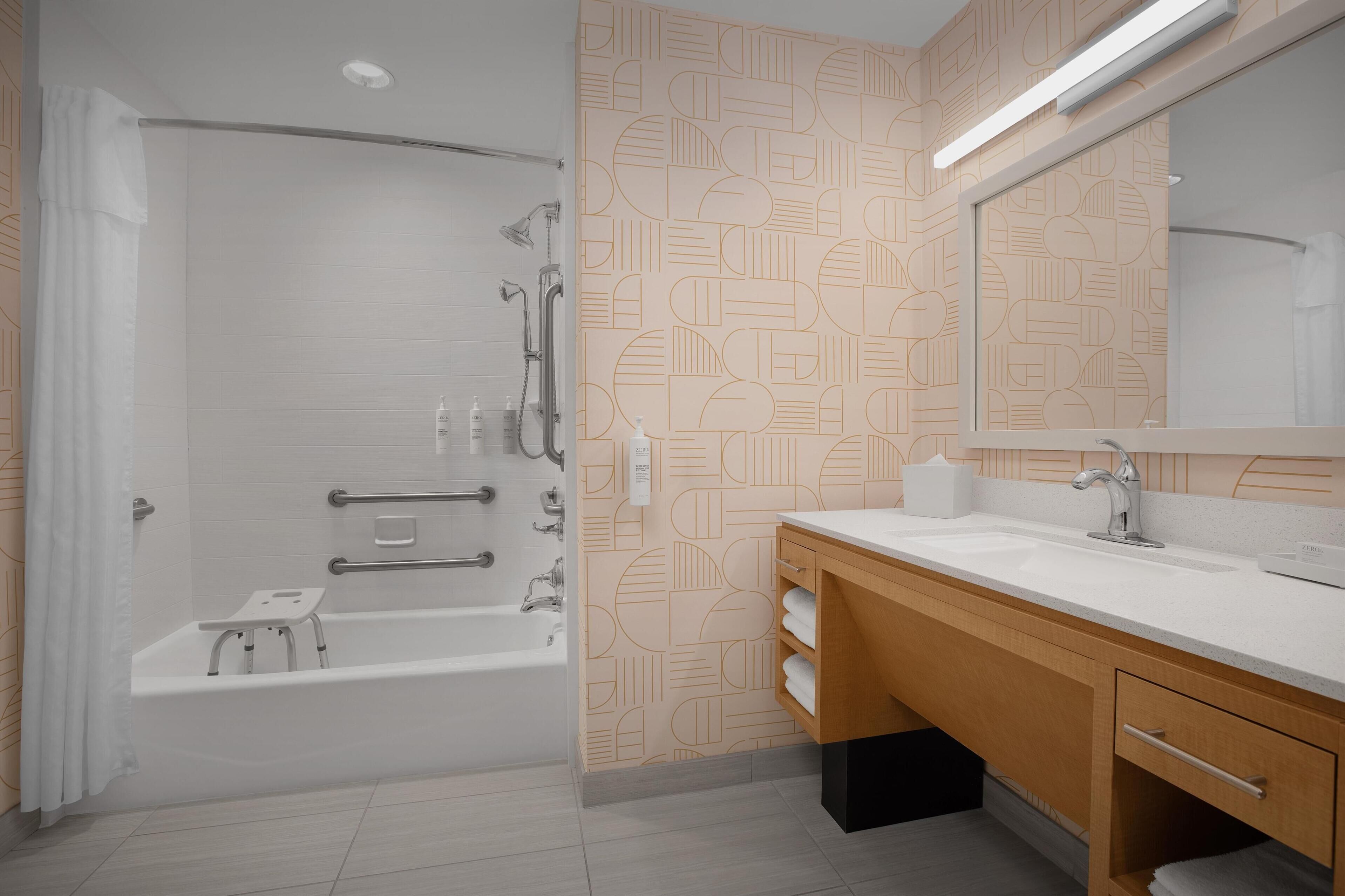 A modern bathroom with a bathtub, shower, and vanity with a mirror.